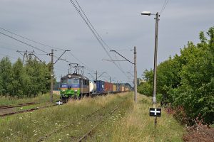 Lokomotywa EU07 ciągnąca wagony towarowe przez pole