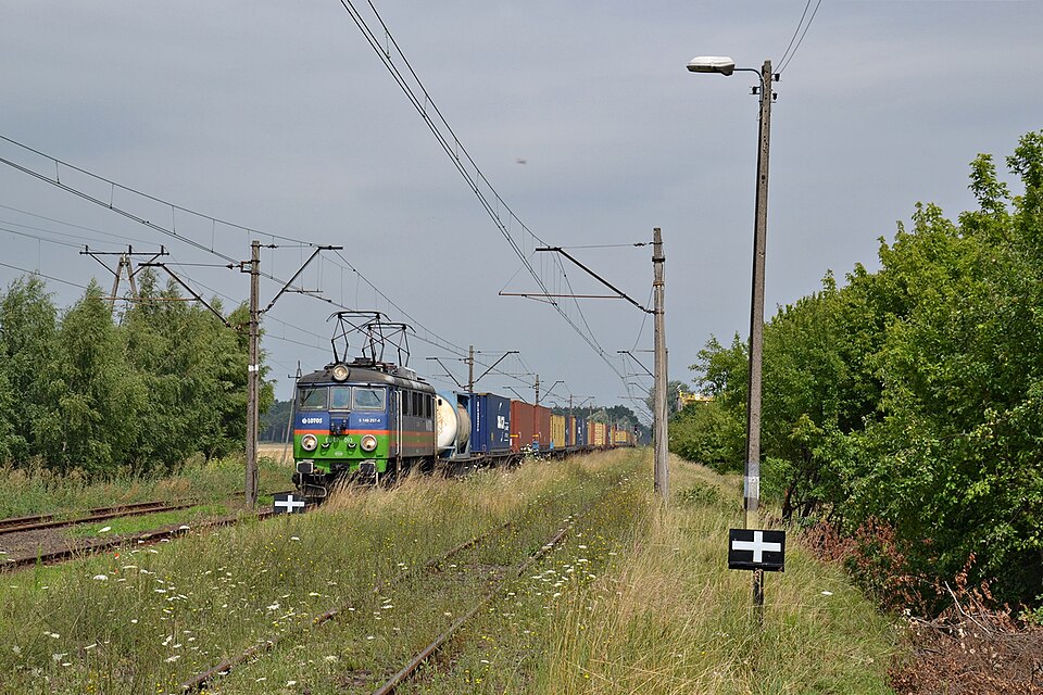 Lokomotywa EU07 ciągnąca wagony towarowe przez pole
