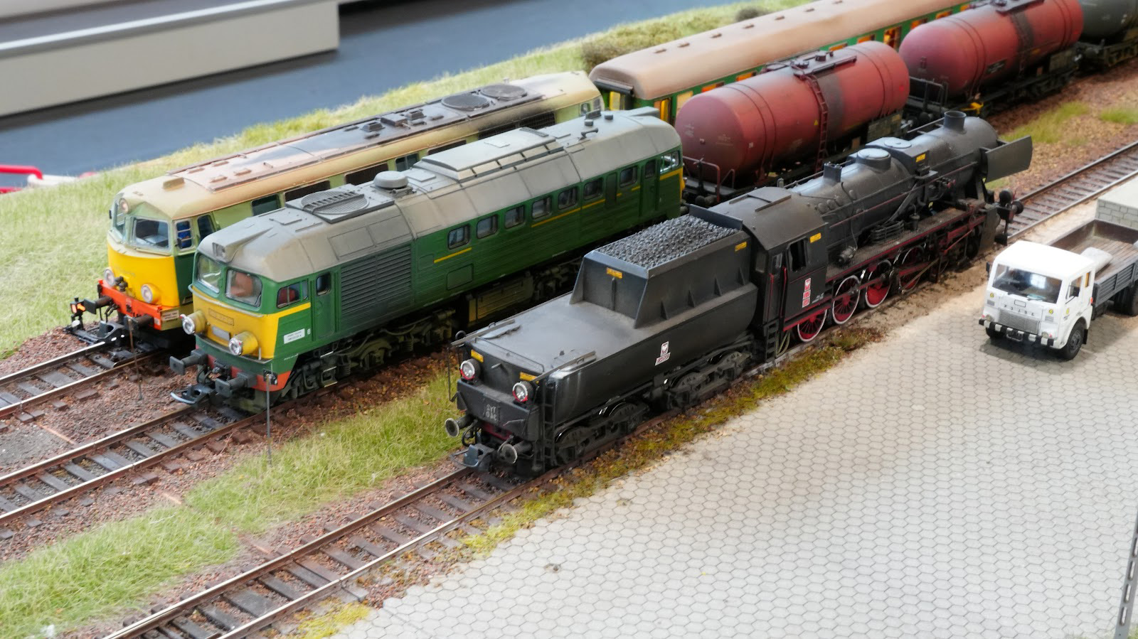 Trzy lokomotywy na modelowej stacji z wagonami i ciężarówką Star – BGM